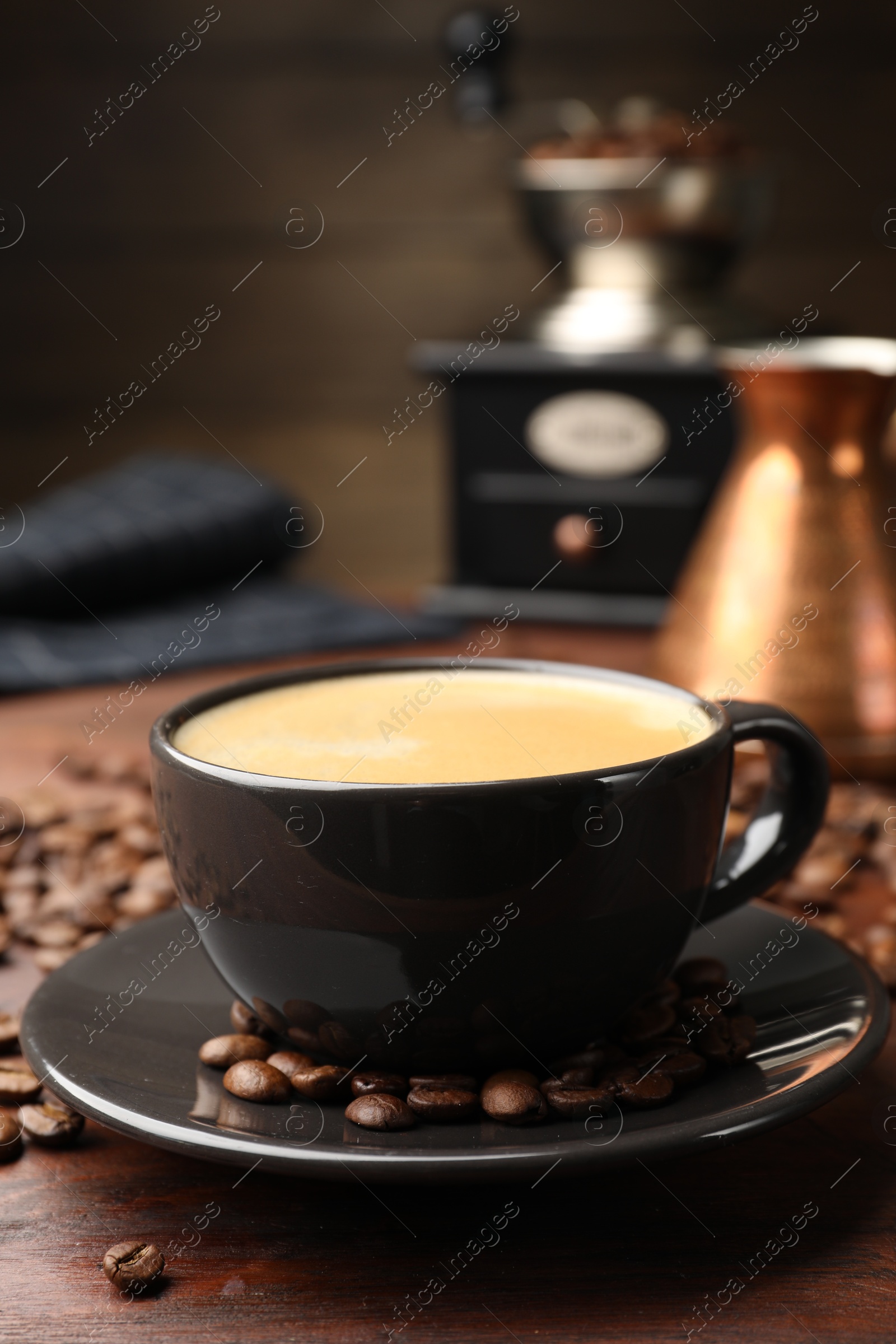 Aromatic coffee in cup, beans, cezve and grinder on wooden table, closeup Photo of Aromatic coffee in cup, beans, cezve and grinder on wooden table, closeup
