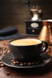 Photo of Aromatic coffee in cup, beans, cezve and grinder on wooden table, closeup