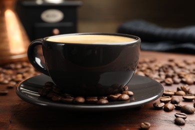 Photo of Aromatic coffee in cup and beans on wooden table, closeup