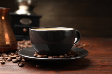 Photo of Aromatic coffee in cup, beans, cezve and grinder on wooden table, closeup
