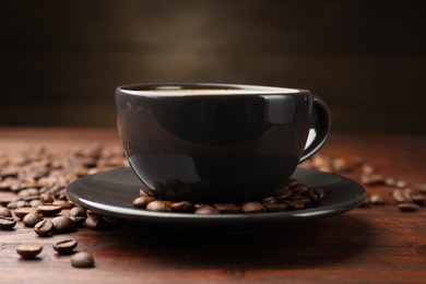 Photo of Aromatic coffee in cup and beans on wooden table, closeup
