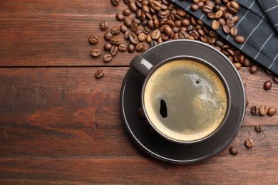 Photo of Aromatic coffee in cup and beans on wooden table, flat lay. Space for text
