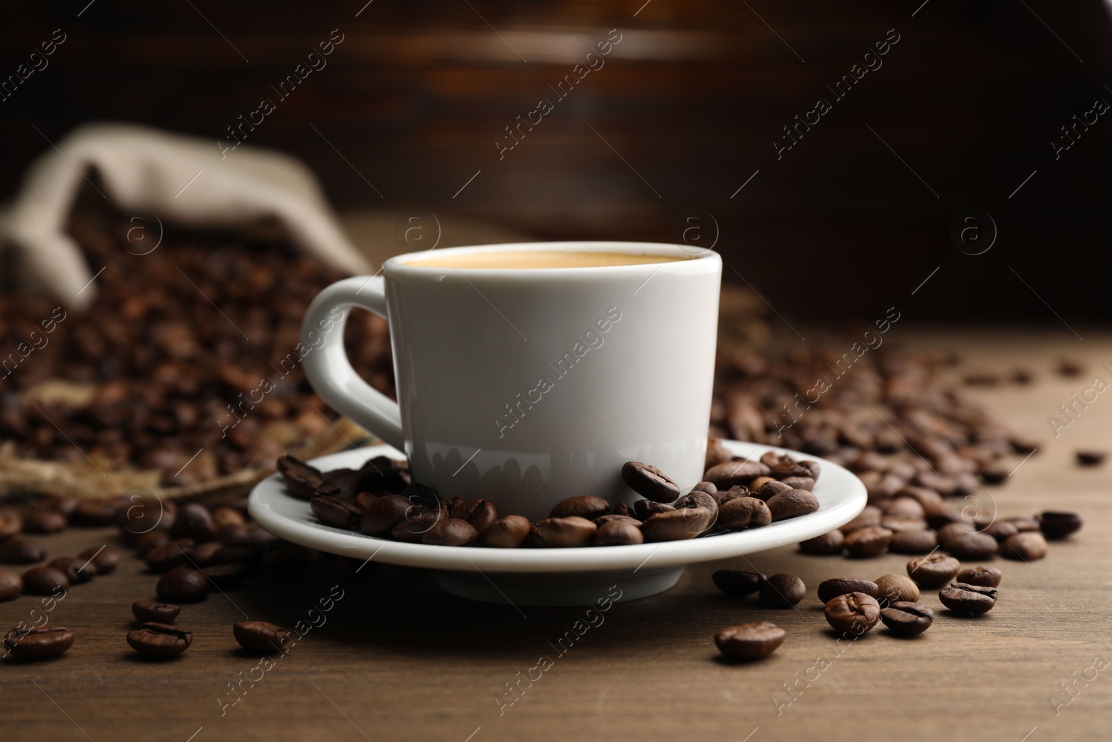 Aromatic coffee in cup and beans on wooden table, closeup Photo of Aromatic coffee in cup and beans on wooden table, closeup