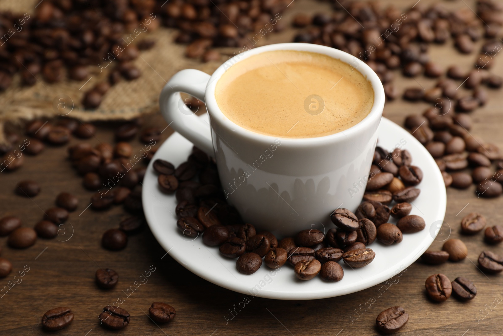 Aromatic coffee in cup and beans on wooden table, closeup Photo of Aromatic coffee in cup and beans on wooden table, closeup
