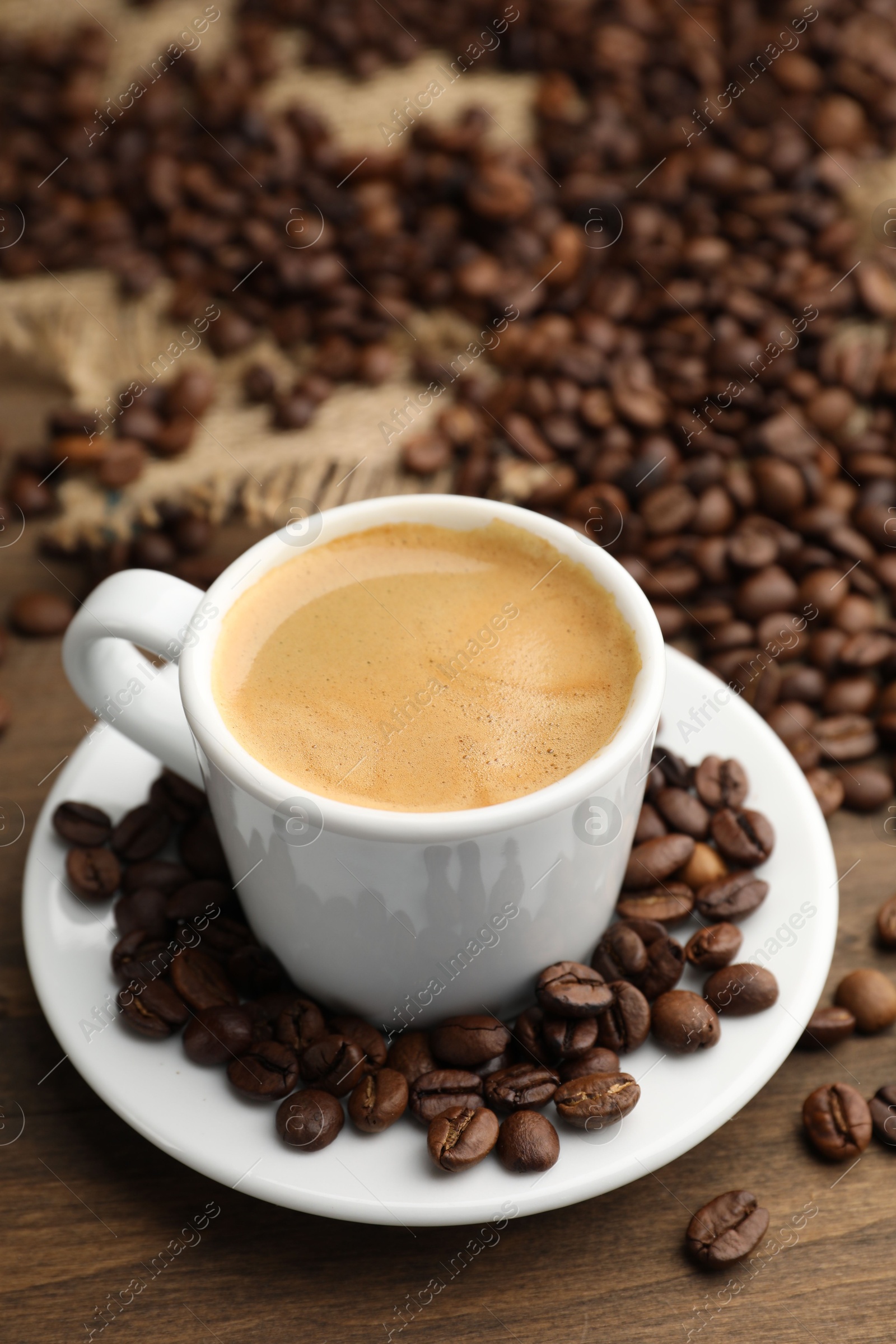 Aromatic coffee in cup and beans on wooden table, closeup Photo of Aromatic coffee in cup and beans on wooden table, closeup
