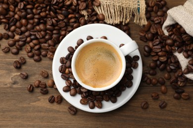 Photo of Aromatic coffee in cup and beans on wooden table, flat lay