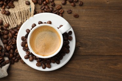 Photo of Aromatic coffee in cup and beans on wooden table, flat lay. Space for text
