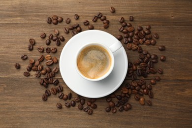 Photo of Aromatic coffee in cup and beans on wooden table, flat lay