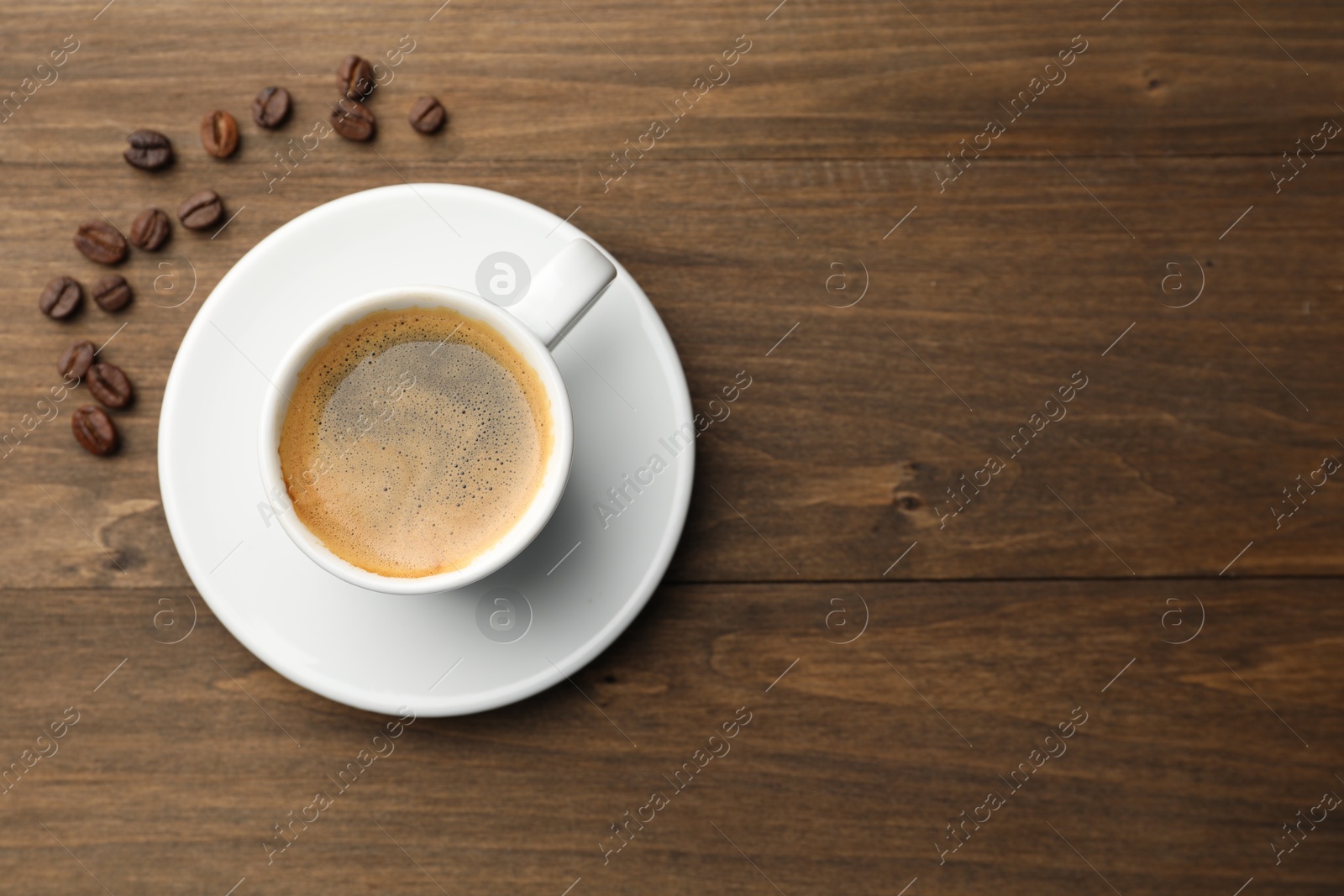 Aromatic coffee in cup and beans on wooden table, flat lay. Space for text Photo of Aromatic coffee in cup and beans on wooden table, flat lay. Space for text