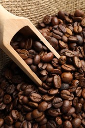 Photo of Aromatic coffee beans and scoop in burlap bag, above view