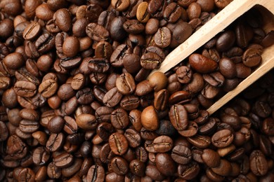 Photo of Aromatic coffee beans and wooden scoop as background, top view