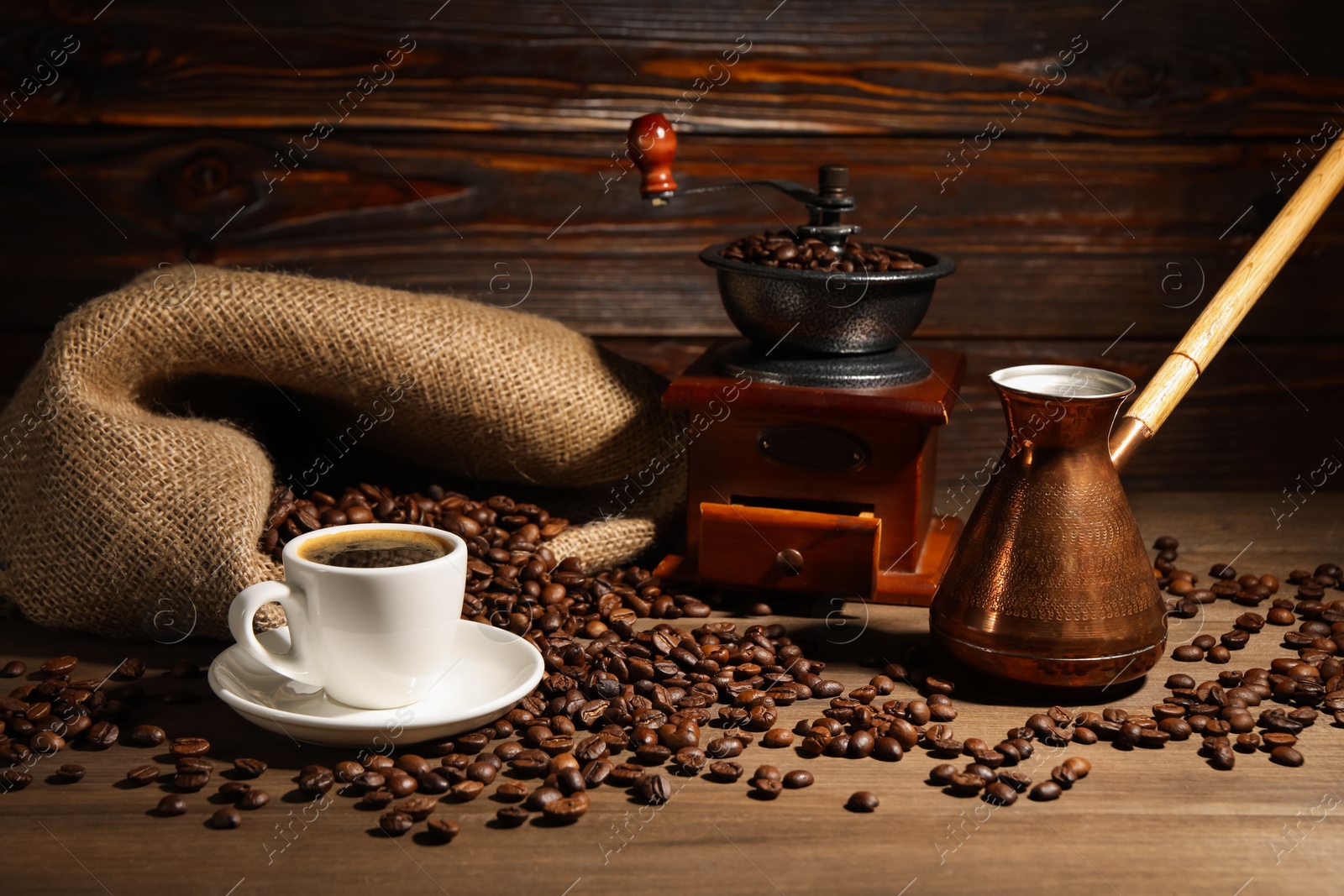 Photo of Aromatic coffee in cup, beans, cezve and grinder on wooden table