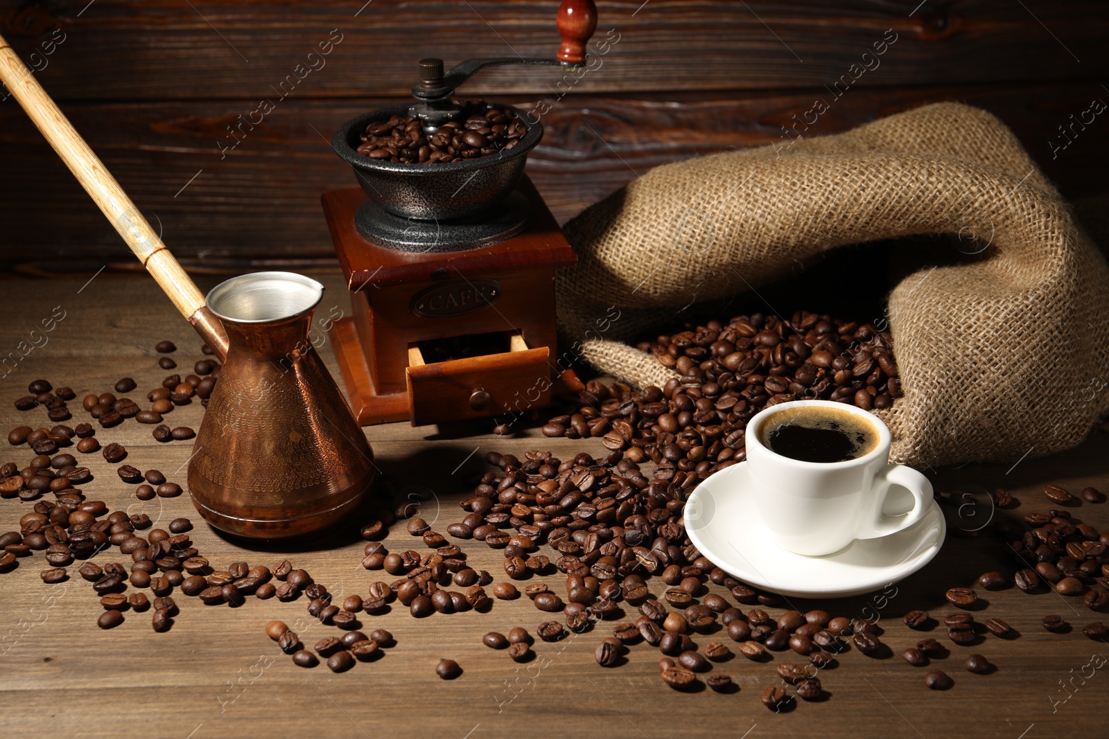 Photo of Aromatic coffee in cup, beans, cezve and grinder on wooden table