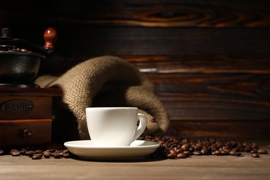 Photo of Cup of drink, coffee beans and grinder on wooden table