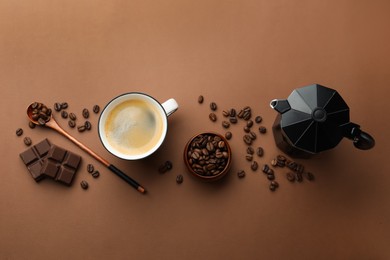 Photo of Aromatic coffee in cup, beans, moka pot and pieces of chocolate on brown background, flat lay