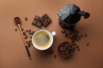 Photo of Aromatic coffee in cup, beans, moka pot and pieces of chocolate on brown background, flat lay