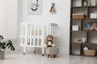 Photo of Baby's room with comfortable crib and teddy bear. Interior design