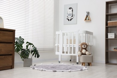 Photo of Baby's room with comfortable crib and teddy bear. Interior design