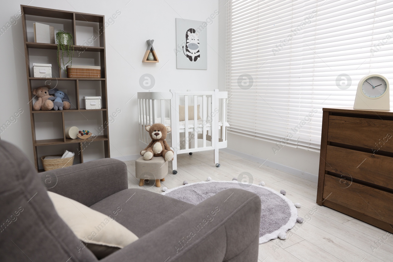 Baby's room with crib and armchair. Interior design Photo of Baby's room with crib and armchair. Interior design