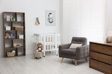 Photo of Baby's room with crib and armchair. Interior design