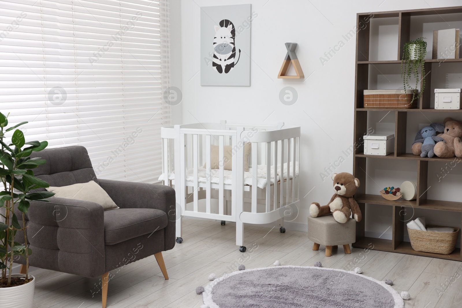 Baby's room with crib and armchair. Interior design Photo of Baby's room with crib and armchair. Interior design