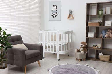 Photo of Baby's room with crib and armchair. Interior design