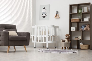 Photo of Baby's room with crib and armchair. Interior design