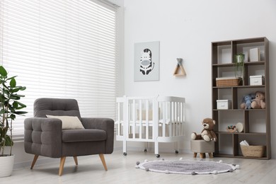 Photo of Baby's room with crib and armchair. Interior design