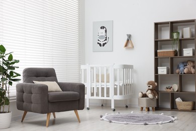 Photo of Baby's room with crib and armchair. Interior design