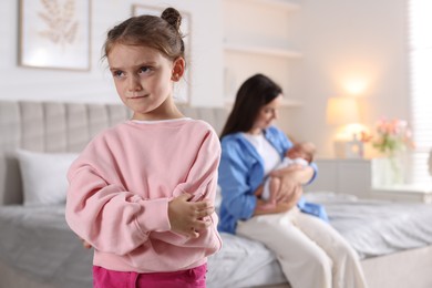 Photo of Jealous little girl upset about mom spending time with newborn baby at home, selective focus