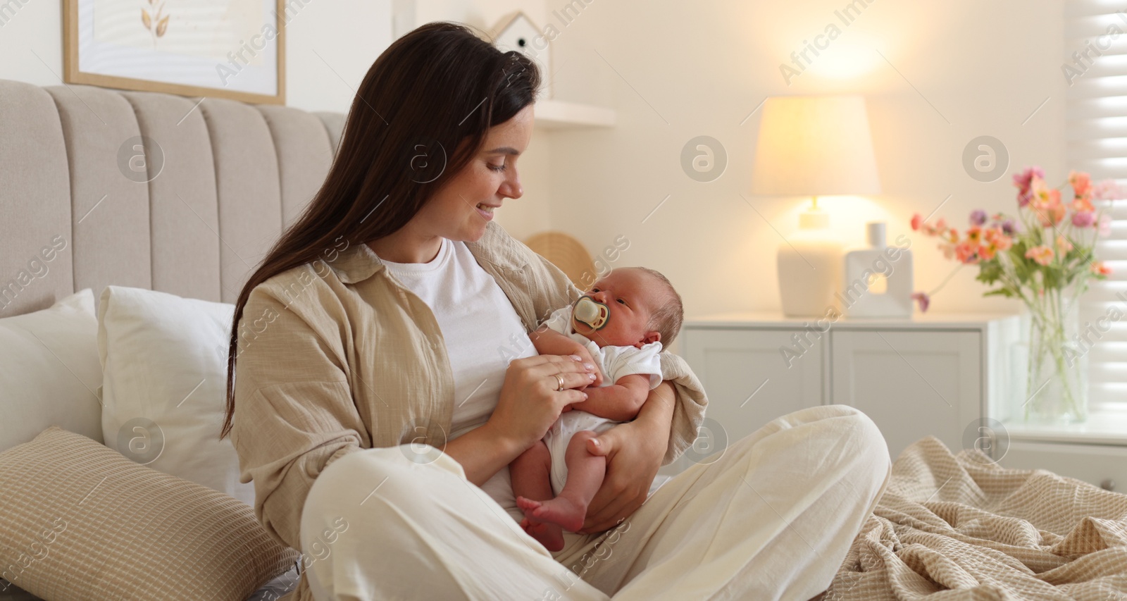 Mother with her newborn baby on bed at home Photo of Mother with her newborn baby on bed at home