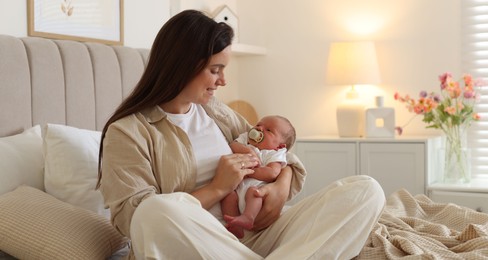 Photo of Mother with her newborn baby on bed at home