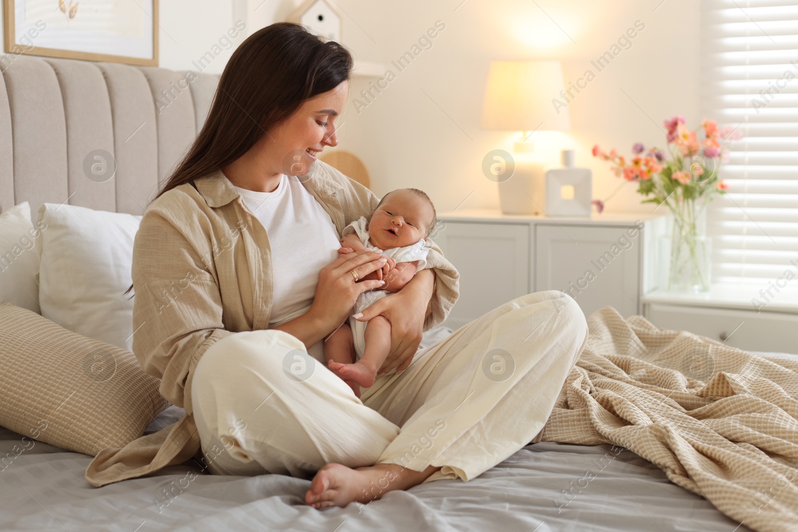 Photo of Mother with her newborn baby on bed at home