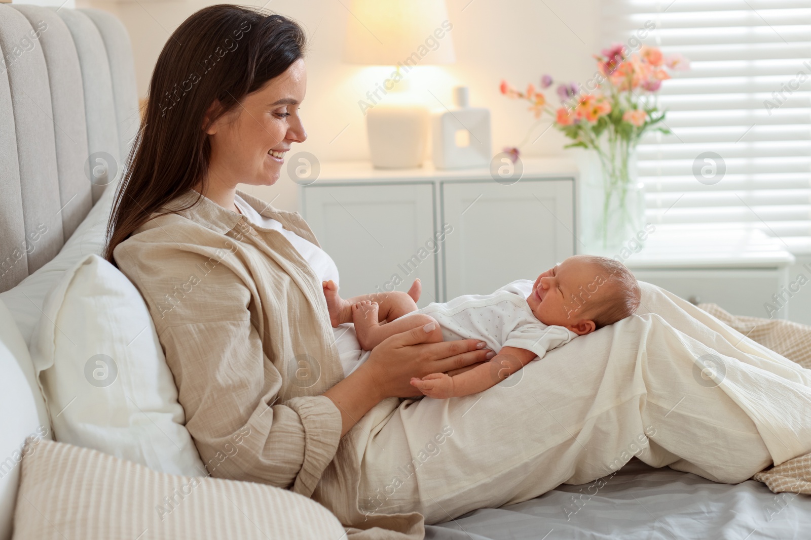 Mother with her newborn baby on bed at home. Space for text Photo of Mother with her newborn baby on bed at home. Space for text