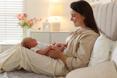 Photo of Mother with her newborn baby on bed at home. Space for text