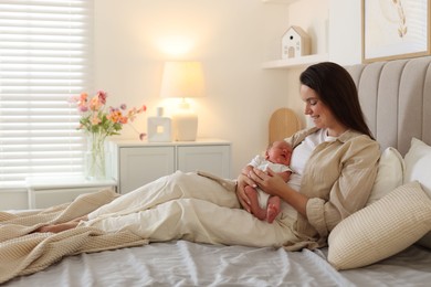 Photo of Mother with her newborn baby on bed at home. Space for text