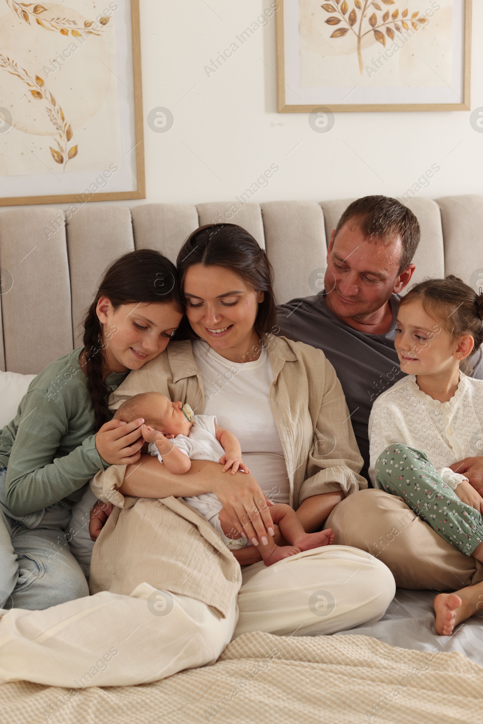 Happy family with newborn baby on bed at home Photo of Happy family with newborn baby on bed at home
