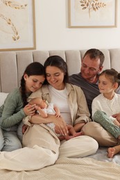 Photo of Happy family with newborn baby on bed at home