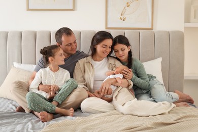 Photo of Happy family with newborn baby on bed at home