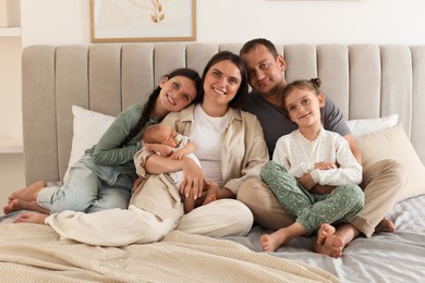 Photo of Happy family with newborn baby on bed at home