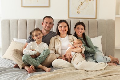 Photo of Happy family with newborn baby on bed at home