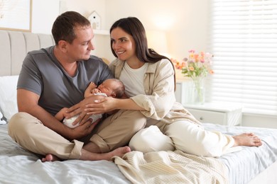 Photo of Happy parents with their newborn baby on bed at home