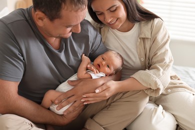 Photo of Happy parents with their newborn baby at home, closeup