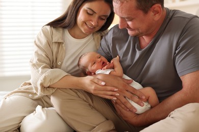 Photo of Happy parents with their newborn baby at home, closeup