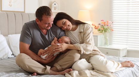 Photo of Happy parents with their newborn baby on bed at home