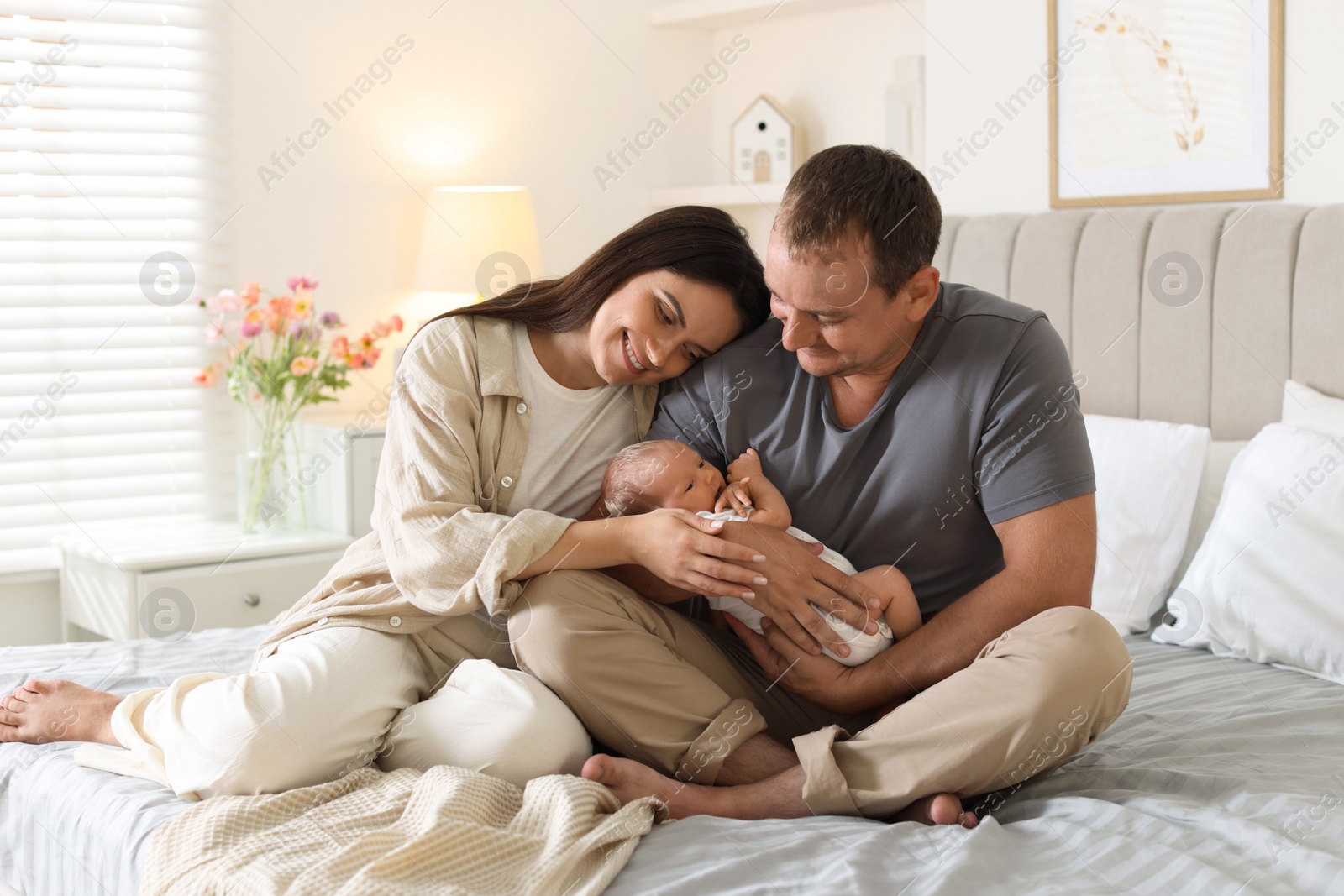 Happy parents with their newborn baby on bed at home Photo of Happy parents with their newborn baby on bed at home