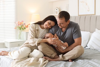 Photo of Happy parents with their newborn baby on bed at home