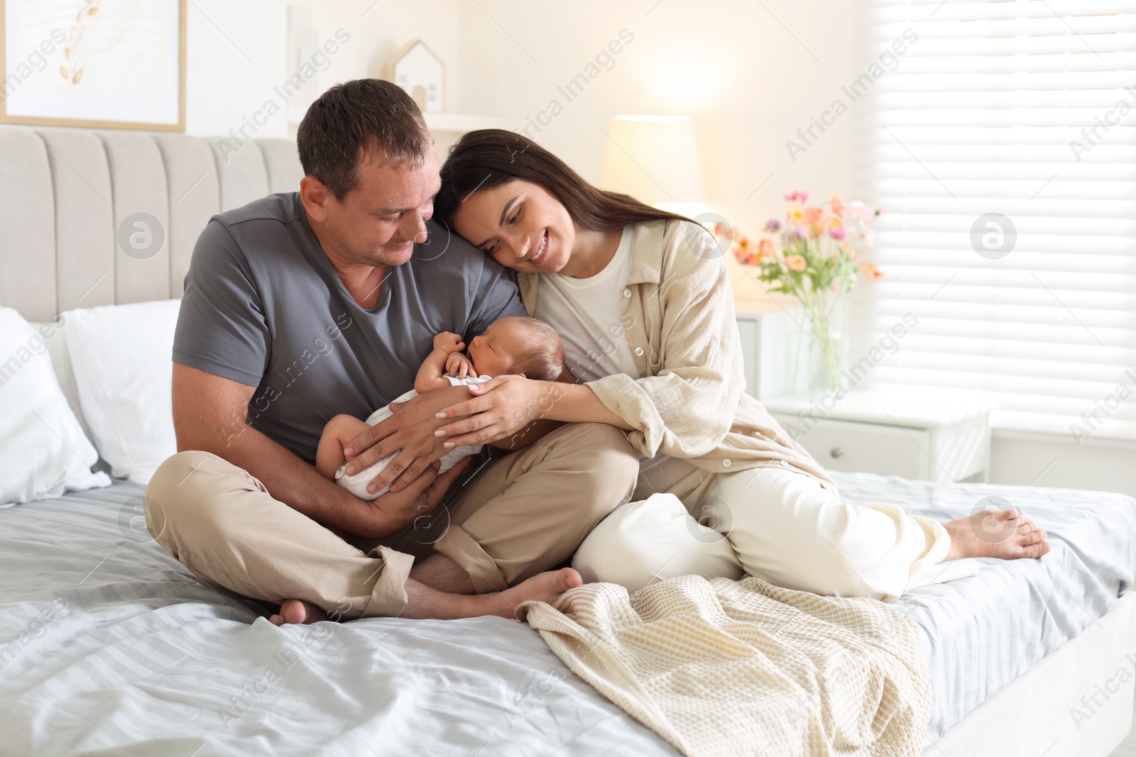 Happy parents with their newborn baby on bed at home Photo of Happy parents with their newborn baby on bed at home