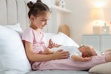 Photo of Big sister with newborn baby on bed at home. Space for text