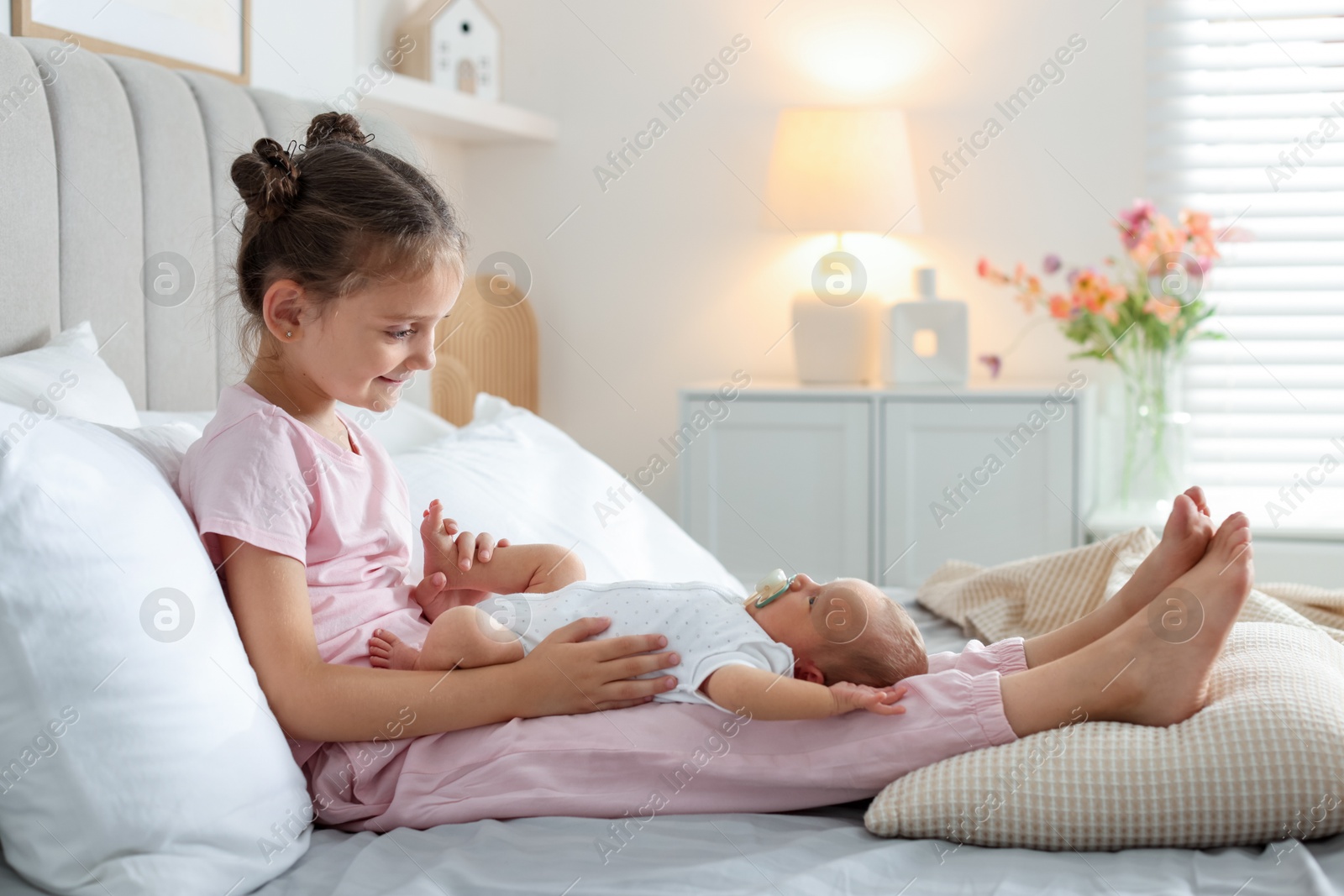 Big sister with newborn baby on bed at home. Space for text Photo of Big sister with newborn baby on bed at home. Space for text